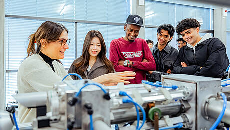 titelbild-mechanical_engineering Studierende aus dem Bachelorstudiengang Mechanical Engineering schauen sich ein Maschinenteil an