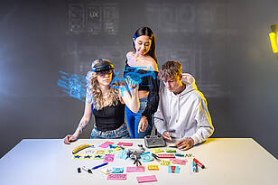 UX-Titelbild Drei Studierende des Studiengangs User Experience, die gemeinsam eine Drohne untersuchen..