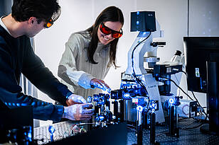 OE-Titelbild Zwei Studierende aus dem Bachelorstudiengang Optical Engineering arbeiten an einem Laser.