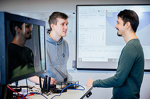 ET-Titelbild Zwei Studierende des Bachelorstudiengangs Elektrotechnik unterhalten sich vor einem Whiteboard.