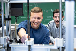 MekA-Titelbild Zwei Studenten aus dem Bachelorstudiengang Mechatronik kompakt durch Anrechnung arbeiten an einer Maschine.