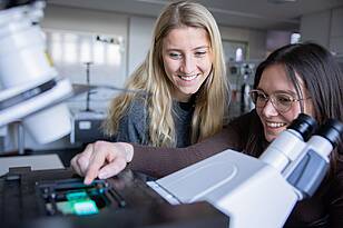 APH-Titelbild Zwei Studentinnen aus dem Masterstudiengang Applied Photonics arbeiten an einem Microskop